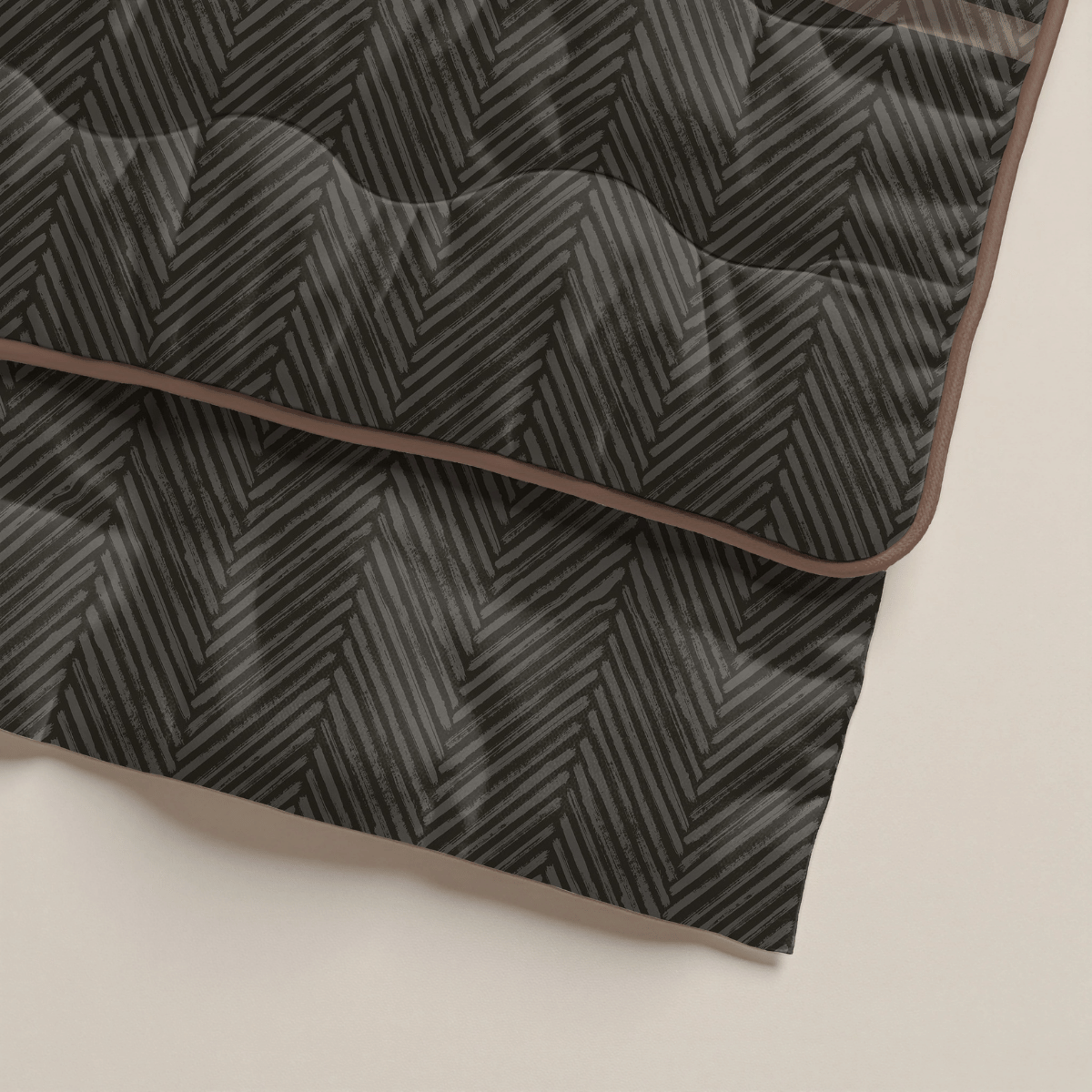 Eine Nahaufnahme einer gefalteten schwarz-grauen Zelesta Royalbed - Brown Stripes Mikrofaser Bettdecke mit Fischgrätmuster und brauner Einfassung, gelegt auf eine helle Oberfläche - eine ideale antiallergische Bettdecke.