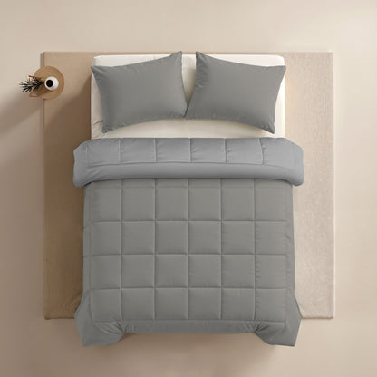 Ein Bett mit dem Zelesta Comfort Duo Kissenbezüge Set von 2 - Grau (80x80cm) und einer passenden grauen Mikrofaser-Bettdecke, von oben gesehen neben einem kleinen runden Nachttisch mit einer Vase.