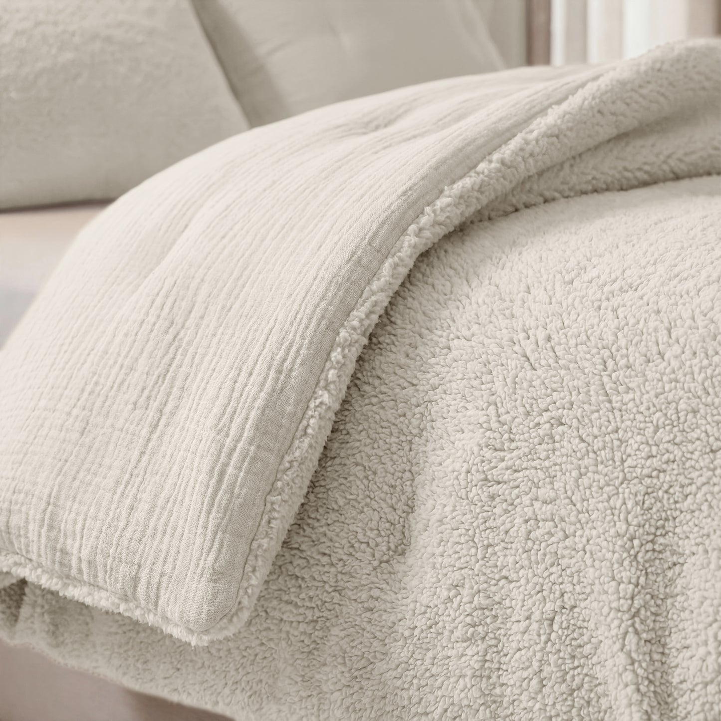 Eine Nahaufnahme eines ordentlich gemachten Bettes mit der Zelesta Teddy Baumwolle Musselin - Beige, einer weichen, flauschigen Steppdecke in hellen Beigetönen.