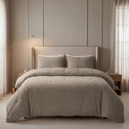 Ein gemütliches Bett mit einer Lampe im Zimmer, geschmückt mit dem Zelesta Teddy Baumwolle Musselin - Taupe, gefertigt aus hochwertiger Musselin-Baumwolle.