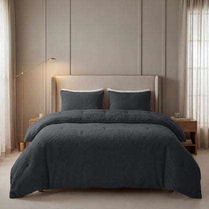 In einem modernen Schlafzimmer mit beigefarbenem Polsterkopfteil, dunkelgrauer Bettwäsche und Nachttischen aus Holz findet sich die Zelesta Teddy Baumwolle Musselin - Anthrazit Bettdecke aus atmungsaktiver Baumwolle mit temperaturregulierender Füllung. Transparente Vorhänge schmücken die hohen Fenster.