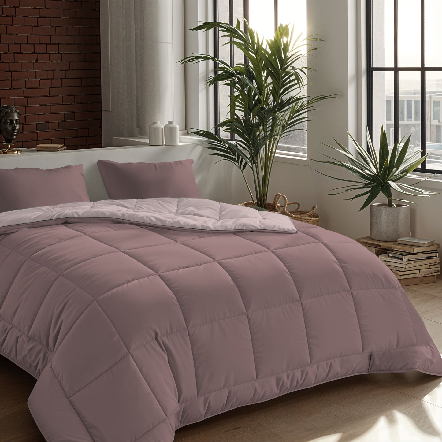 Ein ordentlich gemachtes Bett mit einer Zelesta Comfort Duo Bettdecke - Rosa & Hellrosa und zwei Kissen in einem modernen Schlafzimmer mit großen Fenstern, Topfpflanzen und gestapelten Büchern.