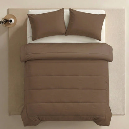 Ein ordentlich gemachtes Bett mit Zelesta Comfort Uni Kissenbezügen Set von 2 - Mokka (80x80cm) und einer passenden Bettdecke, aufgestellt auf einem hellbeigen Teppich neben einem kleinen runden Tisch mit einer Vase in der Ecke.