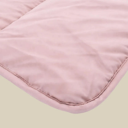 Eine Nahaufnahme der Zelesta Comfort Uni Bettdecke - Altrosa zeigt den hellrosa Steppstoff und die abgerundeten Kanten, die die weiche Textur hervorheben, die für ganzjährigen Komfort sorgt.