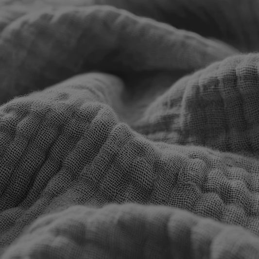 Nahaufnahme von strukturiertem, zerknittertem Musselin Spannbettlaken - Anthrazit in Graustufen, mit ausgeprägten Bindungsmustern und weichen Falten.