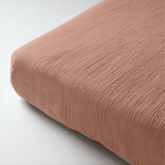 Nahaufnahme des Musselin Spannbettlakens - Dusty-Rose auf einer Matratze. Der weiche, strukturierte Rippenstoff in gedämpftem Rosa sorgt für eleganten Komfort.