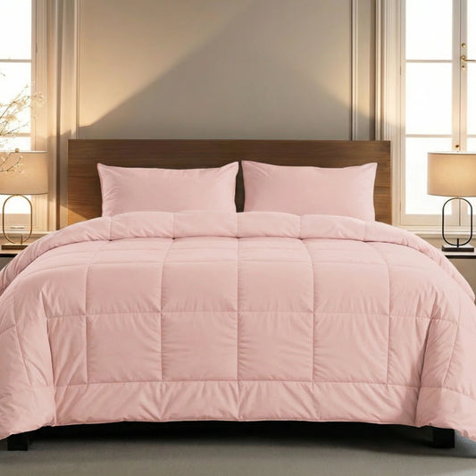 Ein ordentlich gemachtes Bett mit der Zelesta Pure Uni Bettdecke in zartrosa mit passenden Kissen, flankiert von Nachttischen und Lampen, vor einer neutralen Wand mit zwei Fenstern.