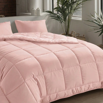 Ein ordentlich gemachtes Bett mit der Zelesta Pure Uni Bettdecke in zartrosa mit zwei passenden Kissen, platziert in der Nähe eines Fensters, das mit Pflanzen und Dekorationsartikeln geschmückt ist.