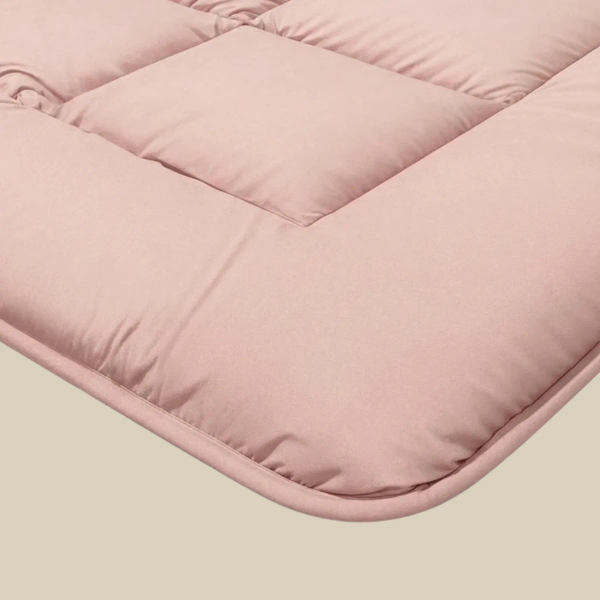 Nahaufnahme der Zelesta Pure Uni Bettdecke in zartrosa, mit weicher Steppstruktur und abgesteppten quadratischen Abschnitten - ideal zur Kombination mit einer Ganzjahres-Bettdecke für kuscheligen Komfort das ganze Jahr über.