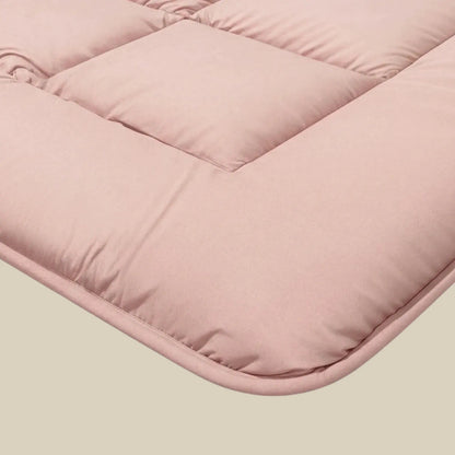 Nahaufnahme der Zelesta Pure Uni Bettdecke in zartrosa, mit weicher Steppstruktur und abgesteppten quadratischen Abschnitten - ideal zur Kombination mit einer Ganzjahres-Bettdecke für kuscheligen Komfort das ganze Jahr über.