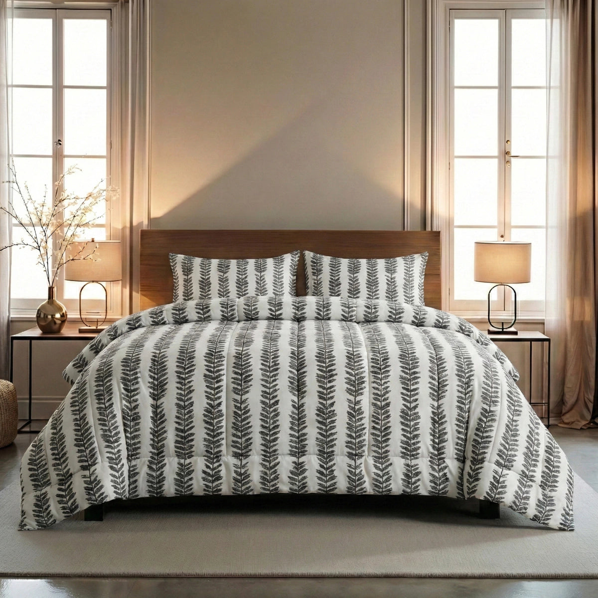 Ein sauber verarbeitetes Zelesta Wonderbed 4 Seasons Double - Savanna Feather mit einer weißen und grauen, blattgemusterten Bettdecke, flankiert von hölzernen Nachttischen und Lampen, in einem sanft beleuchteten Schlafzimmer mit hohen Fenstern und beigen Vorhängen.