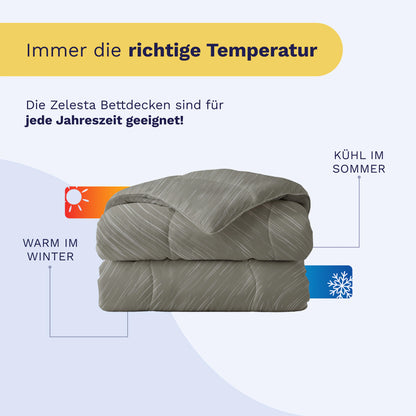 Eine gefaltete graue Bettdecke, das Royalbed Baumwolle - Mellow Stone, wird mit Etiketten gezeigt, die auf die Temperaturregulierung hinweisen - kühl im Sommer und warm im Winter - sowie mit einem deutschen Text, der besagt, dass sie allergikerfreundlich und ganzjährig geeignet ist.